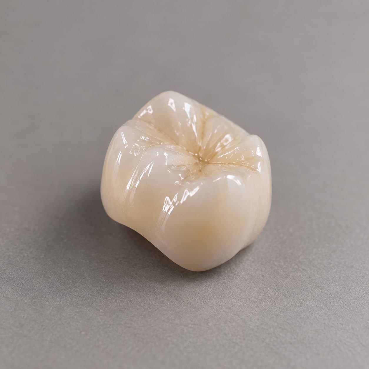 A finished ceramic crown, close up on a neutral background.